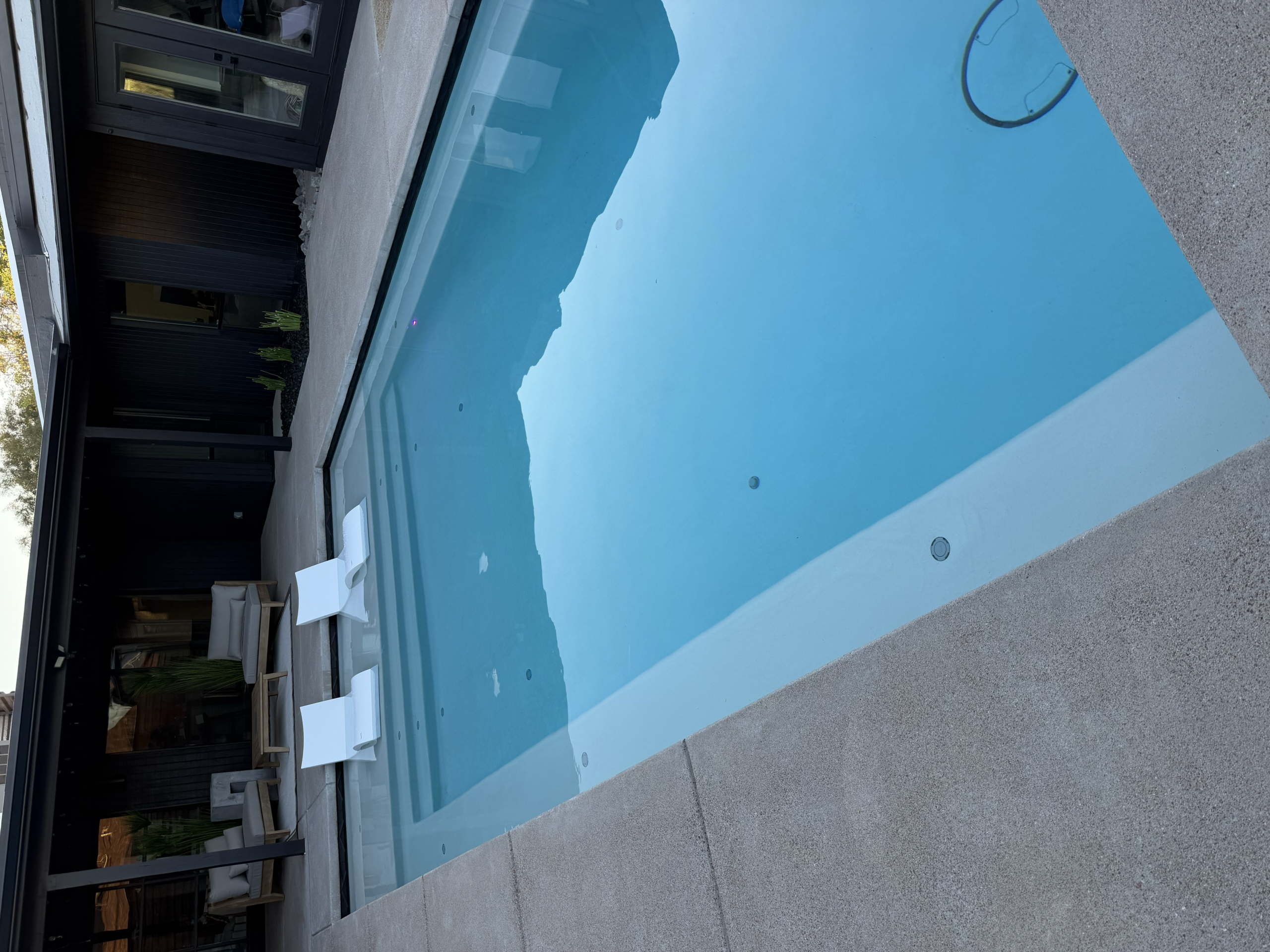 Custom pool installation with waterfall feature and desert-style landscaping.