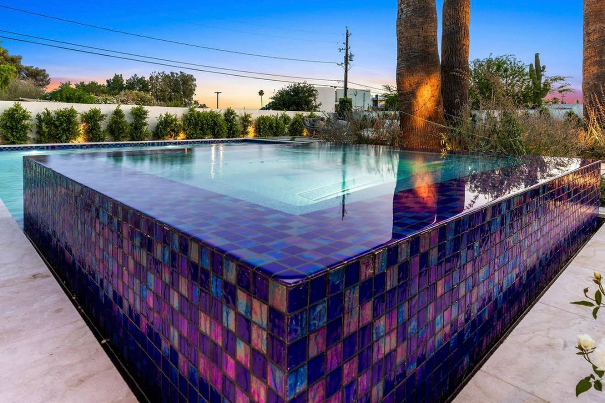 Custom pool installation with waterfall feature and desert-style landscaping.